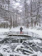 Aerial view, drone photo: Man hiking standing on a bridge over the Briese river in the forest in