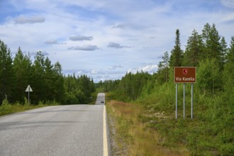 Via Karelia country road with a sign and surrounding trees under blue sky, Kuusamo, Lapland,