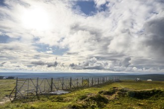 Landscape with vast sky and clouds bounded by a protective fence against snowdrifts Wooden fence