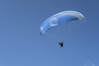 Single paraglider in the blue sky symbolizing freedom and adventure, paraglider near Gudauri,