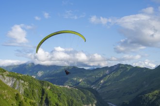 A paraglider in a vast mountain landscape with blue sky and white clouds, paraglider, paraglider
