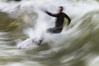 Surfers standing on Eisbach wave in the English Garden Munich, Upper Bavaria, Germany