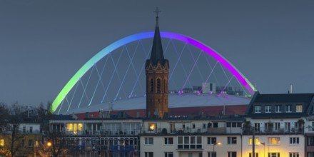 Evening view of residential buildings on the banks of the Rhine, behind them the church tower of St