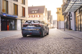Car parked in a quiet old town with cobblestones and old buildings in diffuse light, MG4 electric