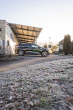 Modern electric car in front of a building on frosty terrain on a clear winter morning, MG4