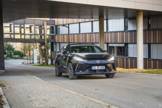 Car in an urban environment in front of a modern office building, contemporary architecture, MG4