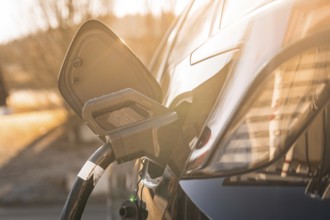 Electric car at a charging station at sunset, modern design emphasized by lighting, MG4 electric