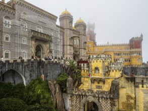 Tourists visiting the palace Palácio Nacional da Pena, foggy day, Sintra, Portugal