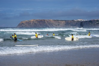 Participants in a surfing course go into the water, beach Praia de Vale Figueiras, village Arrifana