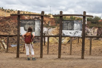 Woman reading explanatory panel, entrance to Mina de Sao Domingos, historic copper open-pit mine,