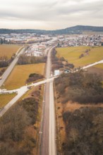 Aerial view of a railway line through snowy fields near a village, using a tamping machine at the