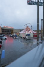 Hofmeister shopping center with circus tent and parked cars at dusk, stuffing machine used at