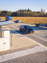 A car moves on a road flanked by other vehicles and trees, MG4 electric car, Deer e-Carsharing,