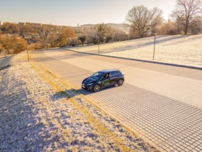A car is parked in an empty, frost-covered parking lot on a sunny winter day, MG4 electric car,