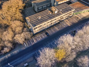 Building complex with empty parking spaces, surrounded by a winter tree landscape, MG4 electric
