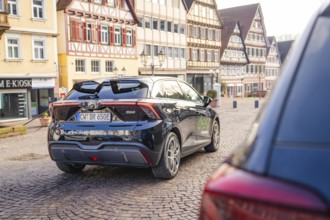 Car in an old town with half-timbered houses and cobblestone streets, MG4 electric car, Deer
