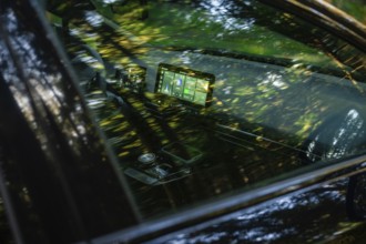 Modern car interior with screens, reflecting forest light and green ambiance, MG4 electric car,