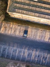 Aerial view of an empty parking lot with a single car next to a building, MG4 electric car, Deer