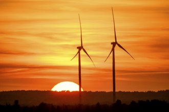 Stemshorn, Lower Saxony, Germany, Two wind turbines stand in the foreground in front of a glowing