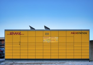 DHL packing station, logo, yellow, with solar cells, solar panels for solar energy supply, sky,