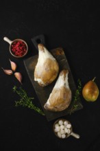 Two duck legs poached in their own rendered fat served with pear, berries, garlic and thyme on a