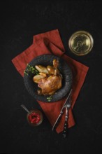 Top view of a plate with roasted duck leg along with caramelised pears and fresh thyme served with