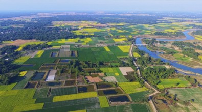 An aerial view reveals a gently curving river winding through the countryside, its silvery surface