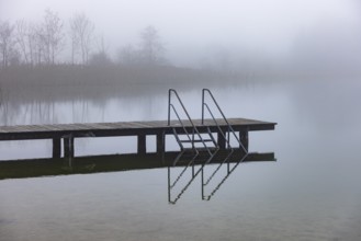 Foggy autumn atmosphere at the lake with wooden footbridge, Irrsee, Salzkammergut, Upper Austria,