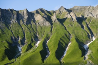 Distinctive rocky ridges with green vegetation under clear, blue air, mountain landscape between