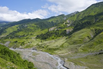 A river runs through wide valleys under a cloudy sky, landscape between Kvesheti and Gudauri, White