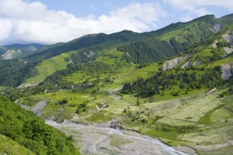Wide green hills and a river criss-cross the mountainous landscape, landscape between Kvesheti and