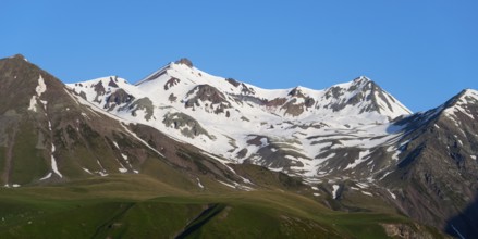Snowy mountain peaks under a clear blue sky, landscape between Kvesheti and Gudauri,
