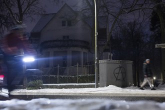 A wall with an anarchy symbol stands in front of a dark villa during the extensive power outage in