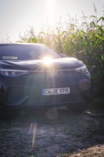 Black car in front of a corn field with low sun in a rural area, VW ID5 electric car, deer e-car