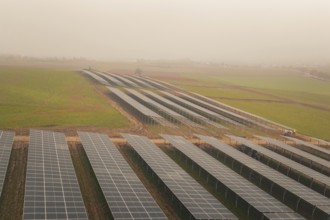 Rows of solar panels on vast green fields, focus on sustainability, energy transition, construction