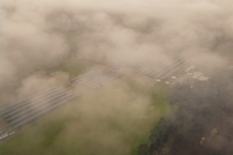 Solar systems in a foggy field landscape, diffuse view through thick fog, energy revolution,