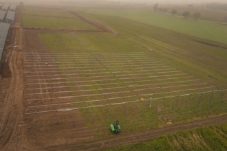 Foggy fields with solar system installation in the foreground, machines in use, energy revolution,
