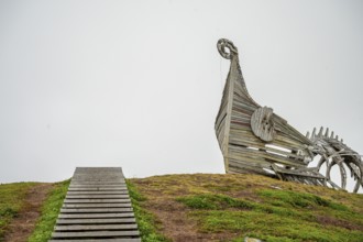 Wooden staircase leads to a sculptural wooden structure on a hill, sculpture by Drakkar Vardø. The