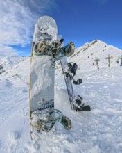Snowboards planted upright in deep powder at a high altitude ski resort, framed by snow covered