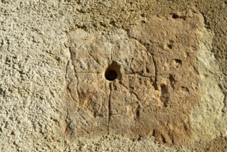 A close view showing a medieval mass dial carved into the exterior wall of St. Saturninus Church.