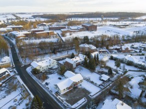 Snowy village with houses, roads and surrounding winter landscape, aerial view, Oelsburg, Ilsede
