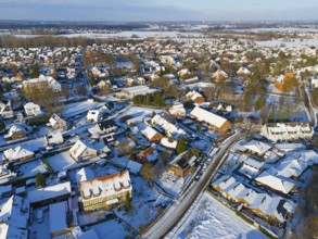 Snowy village landscape with close-standing houses and snow-covered roads from above, aerial view,