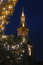 Close-up of church tower with Christmas tree and lights at night, Nagold, Calw district, Black