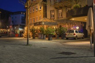 Restaurant with illuminated terrace at night, surrounded by plants and a parked car, Nagold, Calw