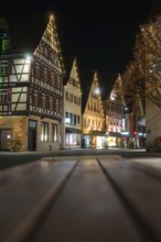 Illuminated half-timbered houses line the Old Town Street at night and create a festive atmosphere,