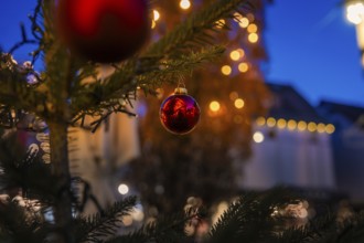 Close-up of a red Christmas ball on a tree, with blurred lights in the background, Nagold, Calw