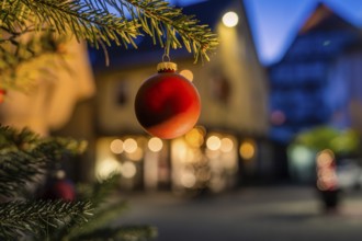 Red Christmas ball hanging on pine branch, blurred illuminated background, Nagold, Calw district,
