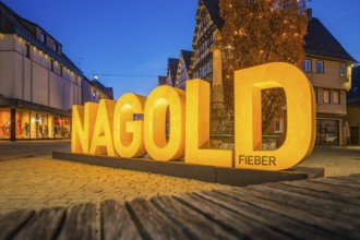 Large illuminated lettering 'Nagold' in an evening city promenade, modern architecture, Nagold,