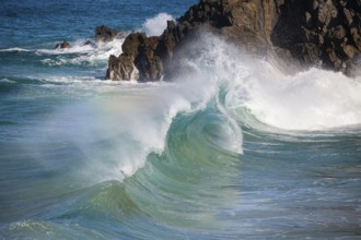 Waves crash against rocks at the mainland's easternmost point, creating rainbows in the ocean spray