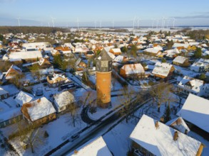Village with a water tower in the midst of a wintry landscape, surrounded by snow-covered houses